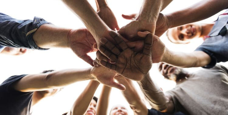 Team of professionals join hands in the middle for a cheer